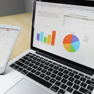 Laptop displaying charts and graphs with tablet calendar for data analysis and planning.